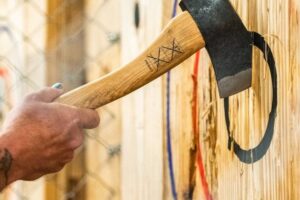 hatchet in a wooden target with a hand starting to remove it.